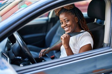 Sokakta kendine güvenen, gülümseyen Afrikalı Amerikalı bir kadın.