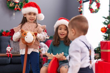 Evde ren geyiği sallama ve at oyuncağıyla oynayan bir grup çocuk.