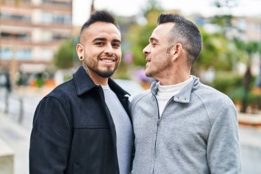 Two men couple smiling confident standing together at street