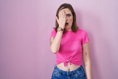 Sarışın, beyaz bir kadın pembe arka planda duruyor. Yarı yüz, göz ve ağız ile esnemekten yorulmuş. Yüzüm acıyor.. 