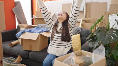 Genç, güzel, İspanyol bir kadın, yeni evinde kazanan bir ifadeyle kanepede oturuyor.