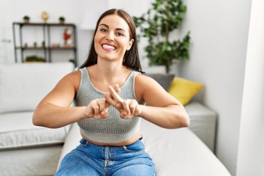 Genç ve güzel İspanyol kadın evdeki kanepede oturan sağırlarla iletişim kuruyor.