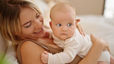 Anne ve kızı yatakta uzanıp, yatak odasında sarılıyorlar.