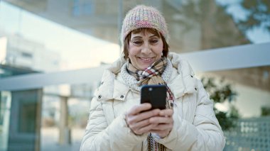 Sokakta akıllı telefon kullanan, kendine güvenen, olgun İspanyol kadın.