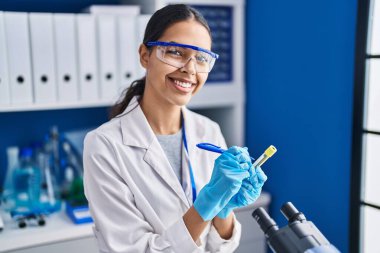 Genç Afrikalı Amerikalı kadın bilim adamı laboratuarda test tüpüne yazdı.