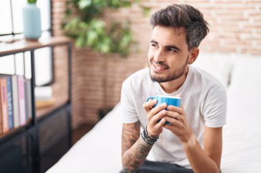 Genç İspanyol adam yatak odasında bir fincan kahve içiyor.