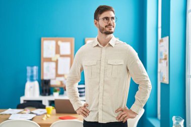 Kafkasyalı genç iş adamı ofiste kendinden emin gülümsüyor.