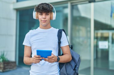 Latin kökenli genç bir öğrenci üniversitede müzik dinlerken touchpad kullanıyor.