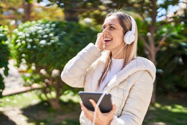 Parkta müzik dinlerken kendinden emin gülümseyen genç bir kadın.