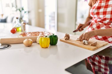 Genç ve güzel İspanyol kadın mutfakta mantar kesiyor.