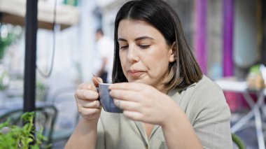 Genç ve güzel İspanyol kadın kahve içiyor açık hava kafeteryasında masada oturuyor.