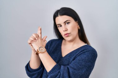 Genç esmer kadın, izole edilmiş arka planda duruyor. Elinde sembolik bir silahla el hareketleriyle cinayet silahlarıyla, kızgın bir yüzle oyun oynuyor. 