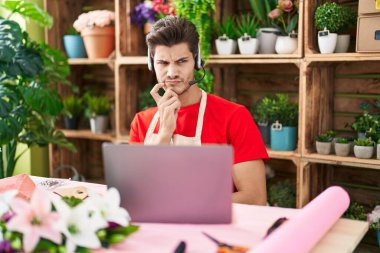 Çiçekçide çalışan Latin asıllı genç bir adam. Video çekiyor. Kuşkuya odaklanmış düşünüyor. 