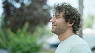 Young hispanic man smiling confident looking to the side at street