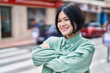 Young chinese woman smiling confident standing with arms crossed gesture at street