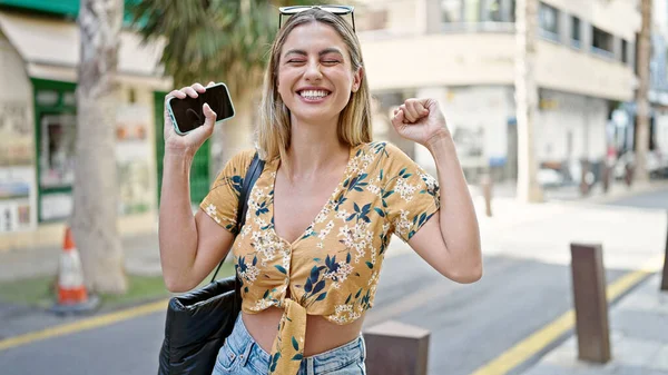 Молодая Блондинка Использует Смартфон Выражением Победителя Улице — стоковое фото
