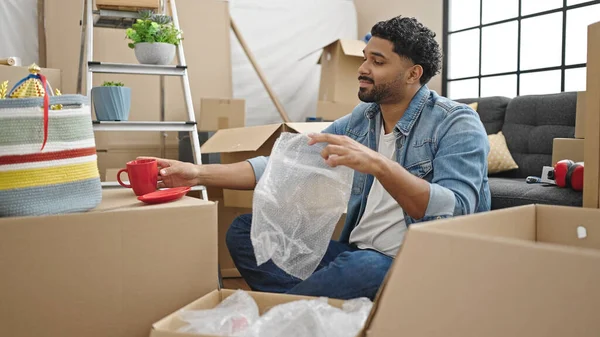 African american man packing cardboard box at new home