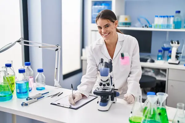 Νεαρή Όμορφη Ισπανίδα Επιστήμονας Χρησιμοποιώντας Μικροσκόπιο Γραφής Έγγραφο Στο Εργαστήριο — Φωτογραφία Αρχείου