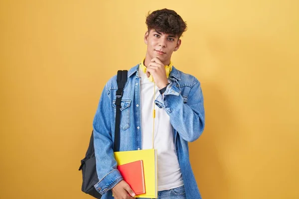 Latynoski Nastolatek Noszący Studencki Plecak Trzymający Książki Ręką Podbródku Myślący — Zdjęcie stockowe