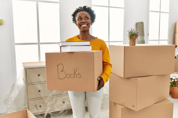 African American Woman Smiling Confident Holding Books Package New Home — Stock Photo, Image