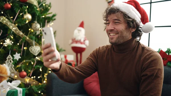 Young Hispanic Man Using Smartphone Sitting Sofa Christmas Tree Home — ストック写真