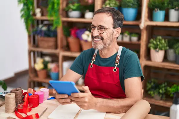 Middle age man florist smiling confident using touchpad at florist