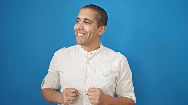 Mladý Hispánec Muž Usměvavý Sebevědomě Dívá Stranu Přes Izolované Modré — Stock fotografie