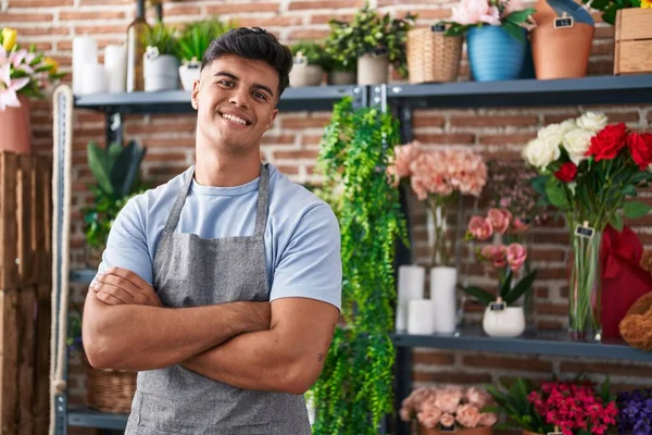 Young hispanic man florist smiling confident standing with arms crossed gesture at flower shop
