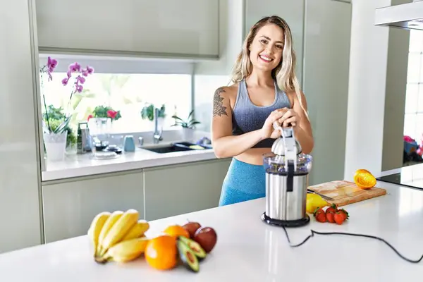 Young woman smiling confident using blender at kitchen