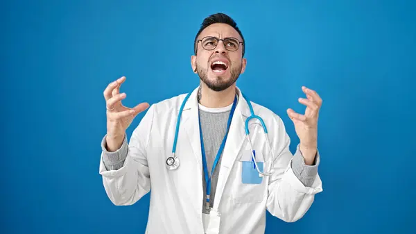 Hispanischer Arzt Wütend Und Gestresst Über Isolierten Blauen Hintergrund — Stockfoto