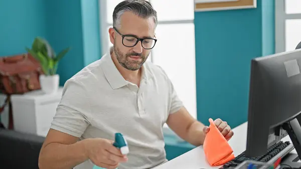 stock image Grey-haired man business worker cleaning table and computer at the office