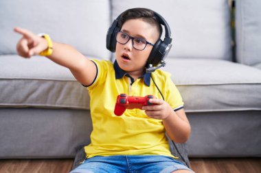 Video oyunu oynayan, kulaklık takan, kulaklık takan, ağzı açık ve şaşırmış bir çocuk. 