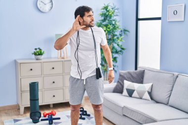 Evde spor giyimli yakışıklı bir Latin adam. Kulağından kulağa gülümsüyor. Dedikoduları ve dedikoduları dinliyor. Sağırlık kavramı. 