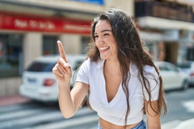 Genç İspanyol kadın gülümsüyor. Kendine güveni tam. Sokakları işaret ediyor.