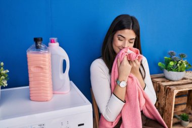 Genç, güzel, İspanyol bir kadın gülümsüyor. Çamaşırhanede temiz kıyafetler kokluyor.