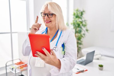 Orta yaşlı, beyaz bir kadın online bir randevuda gülümsüyor bir fikir veya soru işareti ile mutlu bir yüzle, bir numara 