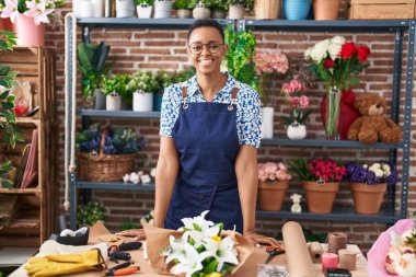 Çiçekçiye bakıp gülümseyen Afrikalı Amerikalı kadın.