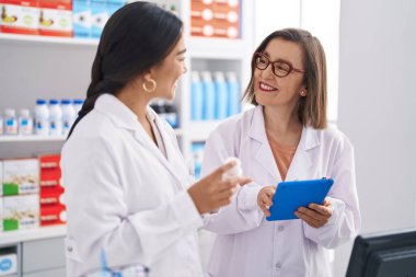 Eczanede dokunmatik ped kullanan iki kadın eczacı.