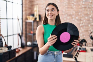 Genç İspanyol kadın müzisyen müzik stüdyosunda vinil disk tutuyor.