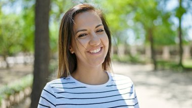 Ortadoğulu kadın parkta kendinden emin gülümsüyor.