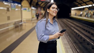 Madrid metro istasyonunda akıllı telefon kullanan güzel İspanyol bir kadın metroda bekliyor.