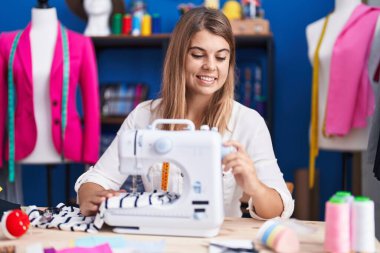 Dikiş atölyesinde dikiş makinesi kullanan kendine güvenen genç bir terzi.