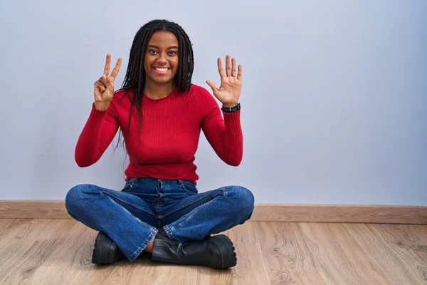 Mladý Africký Američan Copánky Sedí Doma Podlaze Ukazuje Ukazuje Prsty — Stock fotografie