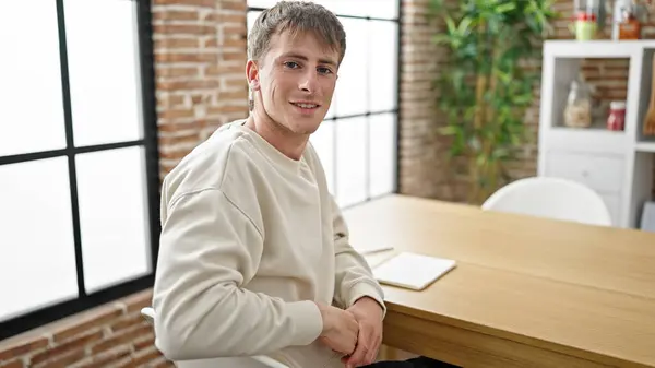 Young caucasian man writing on notebook sitting on table at dinning room