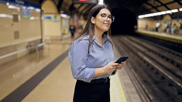 地下鉄の駅でスマートフォンを使用して地下鉄を待っている若い美しいヒスパニック系の女性マドリード — ストック写真
