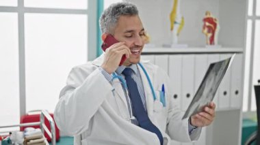 Xray arayan genç İspanyol doktor klinikte akıllı telefondan konuşuyor.