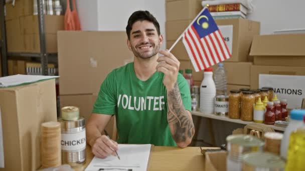 Młody Hiszpan Ochotnik Uśmiecha Się Ufnością Trzymając Flagę Malezji Ośrodku — Wideo stockowe