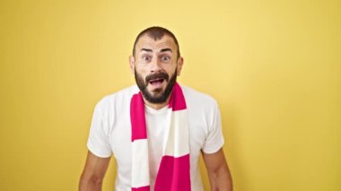 Genç İspanyol futbolu destekleyen adam izole edilmiş sarı arka planı kutluyor.