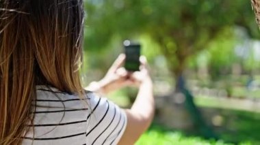 Ortadoğulu kadın parkta tavus kuşuna fotoğraf çekmiş.