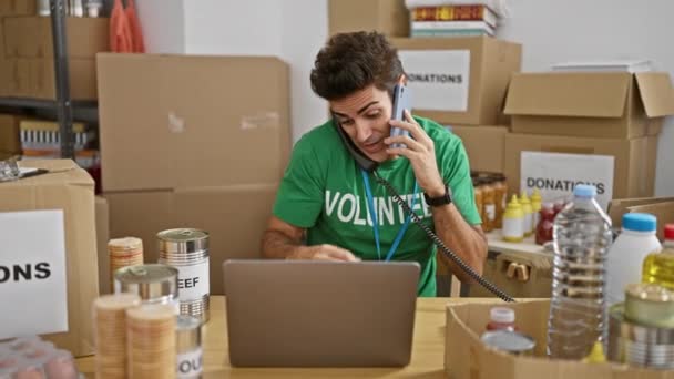 Jovem Hispânico Voluntário Falando Telefone Smartphone Usando Laptop Centro Caridade — Vídeo de Stock